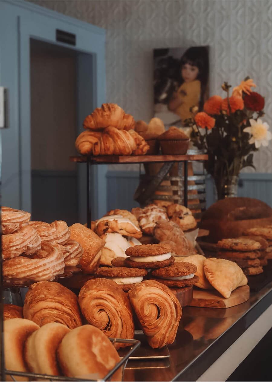 Display of fresh pastries at Middle Street Foods with a vintage photo of baby Emma in the background