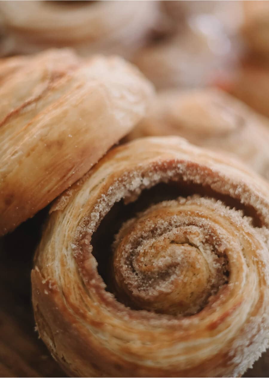 Flaky, spiraled cinnamon danish pastries with a light sugar dusting.