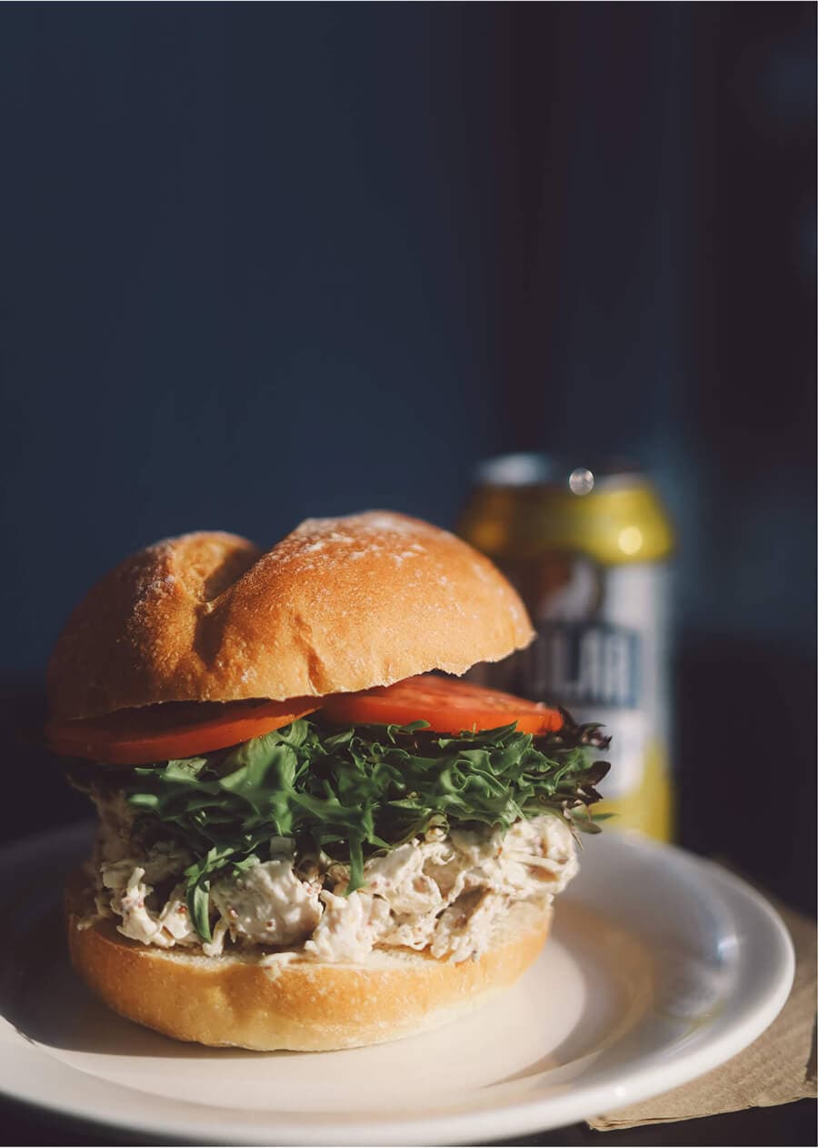 Classic chicken salad sandwich with lettuce and tomato on a fresh roll.