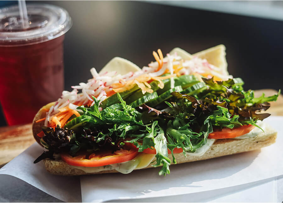 Fresh veggie baguette with lettuce, tomato, cucumber, and shredded carrots.